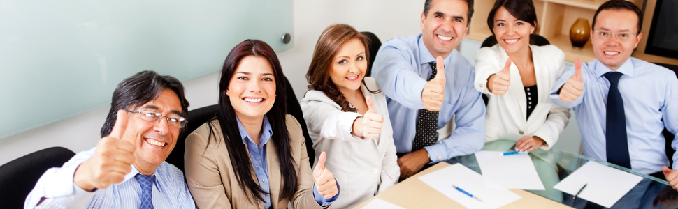 Businesspeople all sitting at a table giving a thumbs up